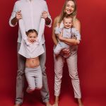 caucasian-family-with-two-children-poses-camera-together-picture-isolated-red-background_132075-9498