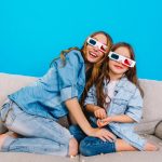 happy-excited-mother-with-cute-pretty-daughter-couch-blue-background-watching-3d-movie-glasses-together-wearing-jeans-clothes-expressing-positivity-happiness-camera_197531-3511